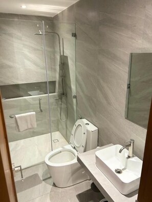 Un baño moderno con ducha envuelta en vidrio, inodoro y lavamanos.