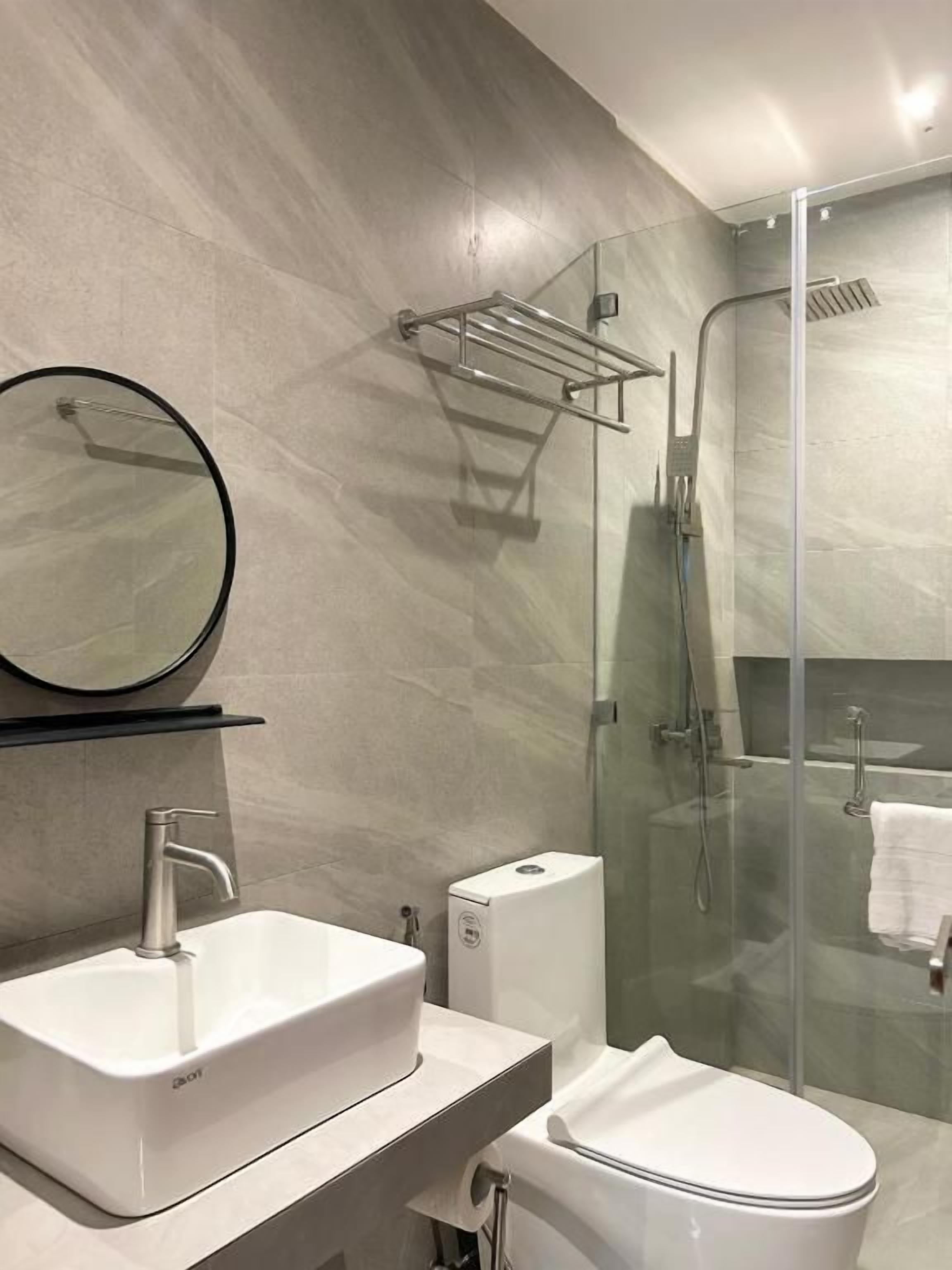 Un baño moderno con ducha envuelta en vidrio, un lavabo blanco y un inodoro.