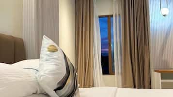 Ein Hotelzimmer mit Bett, Vorhängen, einem Fenster und einem Nachttisch.