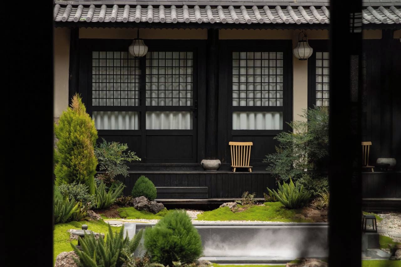 A traditional building with a tiled roof, large windows with grid patterns, and a small wooden bench in front.