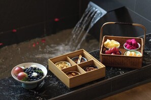 A wooden tray with compartments containing various fruits and a bowl with apples and blueberries.