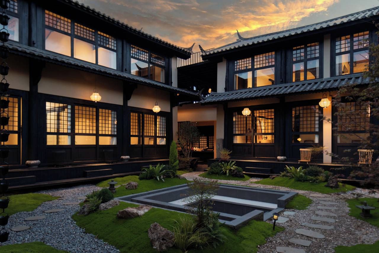 A traditional building with multiple windows and a courtyard with a stone pathway.
