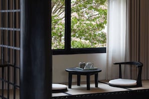 Una habitación con suelo de esteras de tatami, una mesa con tetera y tazas, y dos sillas.