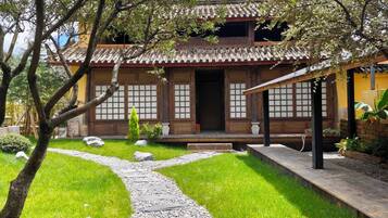 Un edificio tradicional japonés con techo de tejas, puertas de madera y un sendero de piedra que conduce a la entrada.