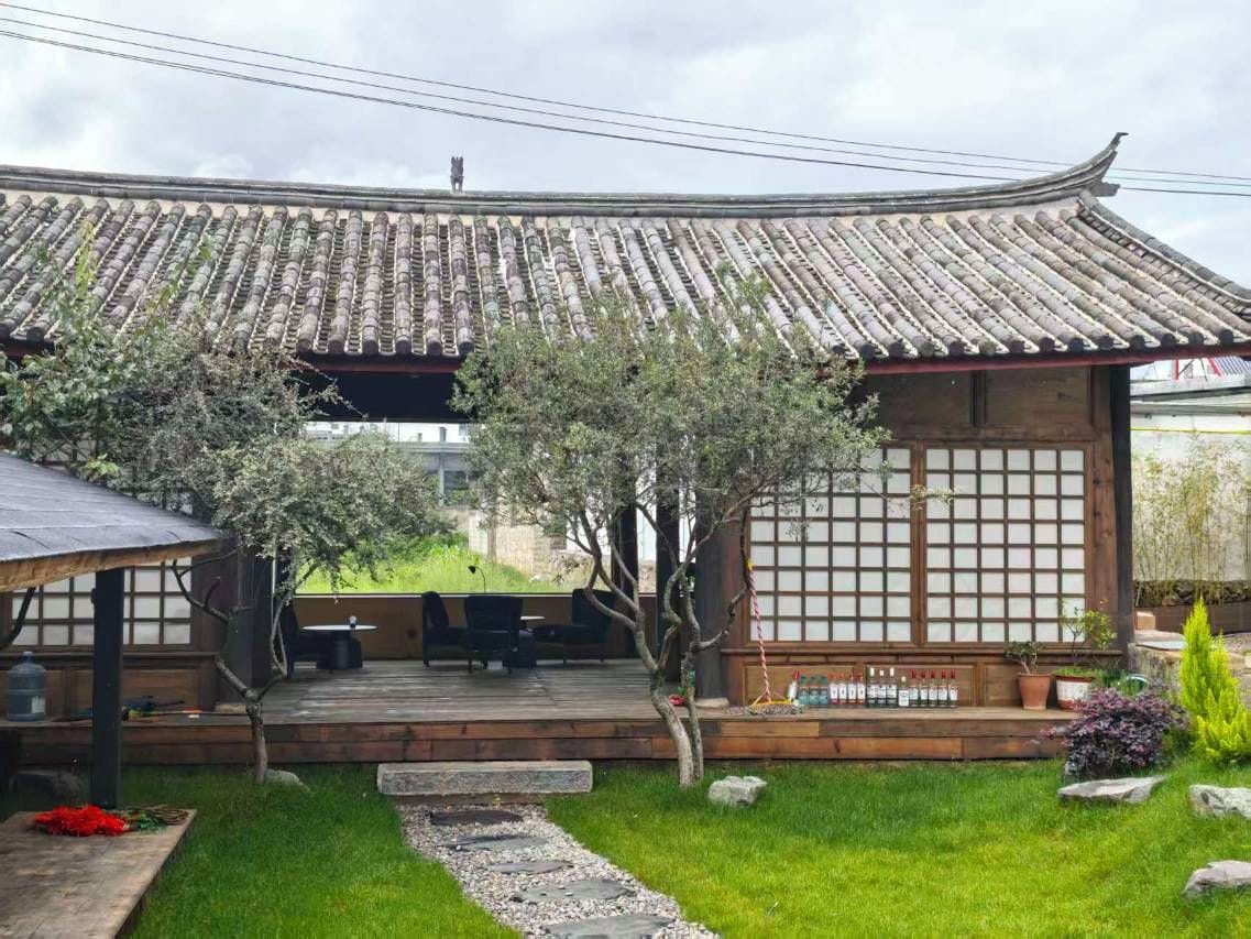 A traditional Japanese building with a tiled roof, a wooden deck, and a stone pathway leading to the entrance.