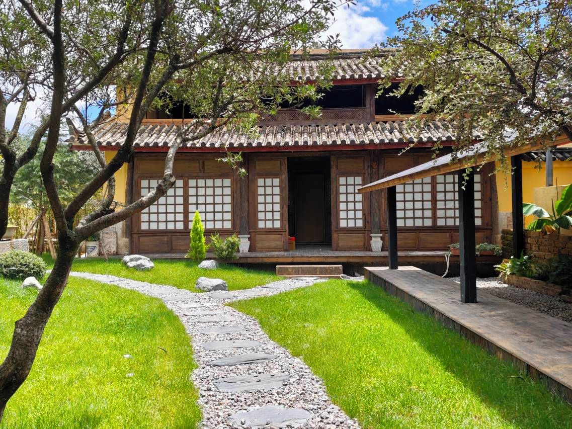A traditional Japanese-style building with a tiled roof, wooden doors, and a stone pathway leading to the entrance.