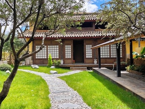Un edificio tradicional japonés con techo de tejas, puertas de madera y un sendero de piedra que conduce a la entrada.