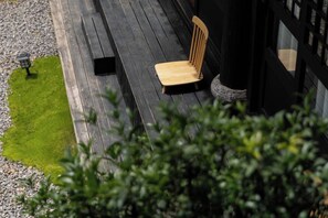 A wooden deck with a single wooden chair, a small black object, and a lamp post.