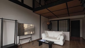 A modern living room with a white sofa, a coffee table, a framed picture on the wall, and a floor lamp.