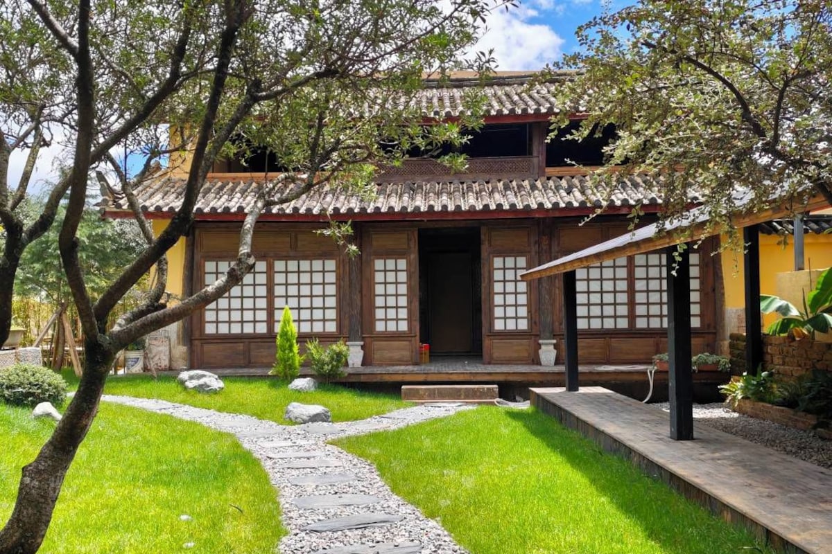 A traditional Japanese-style building with a tiled roof, wooden doors, and a stone pathway leading to the entrance.