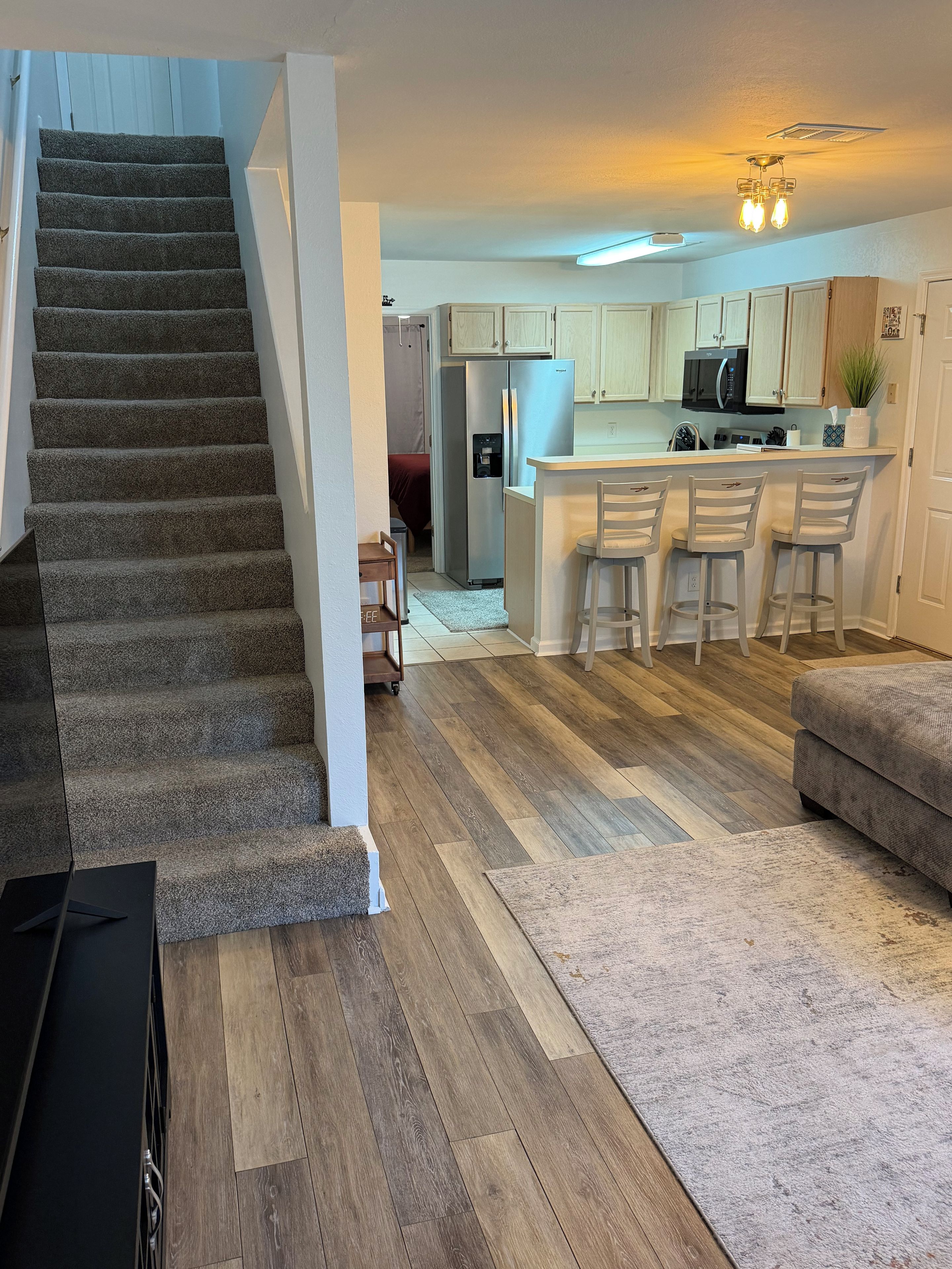 A staircase leading to a living area with a kitchen in the background.