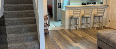 A staircase leading to a living area with a kitchen in the background.