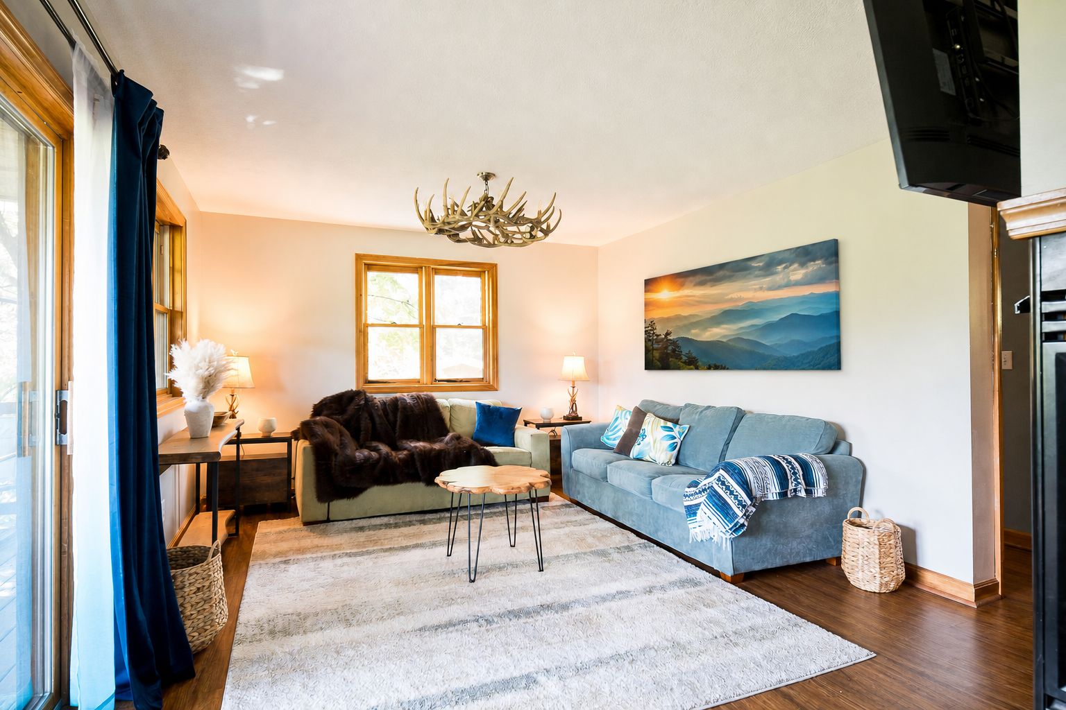 Ein Wohnzimmer mit einer Couch, einem Couchtisch, einer Deckenleuchte, einem Gemälde und einem Fernseher.