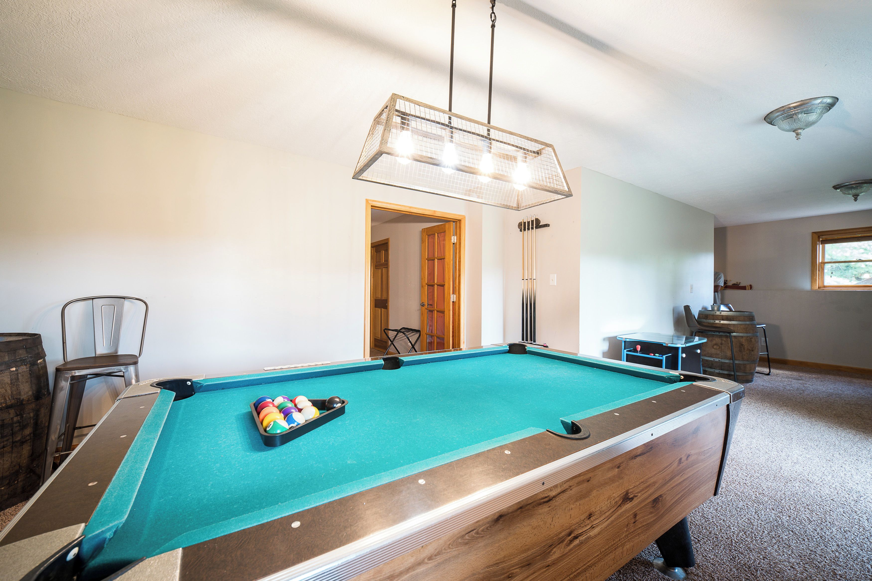 Une table de billard avec différentes sortes de billes, une chaise et un meuble en bois.
