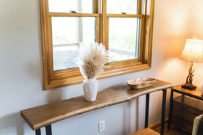 A wooden console table with a vase of dried pampas grass, a bowl, and a lamp.