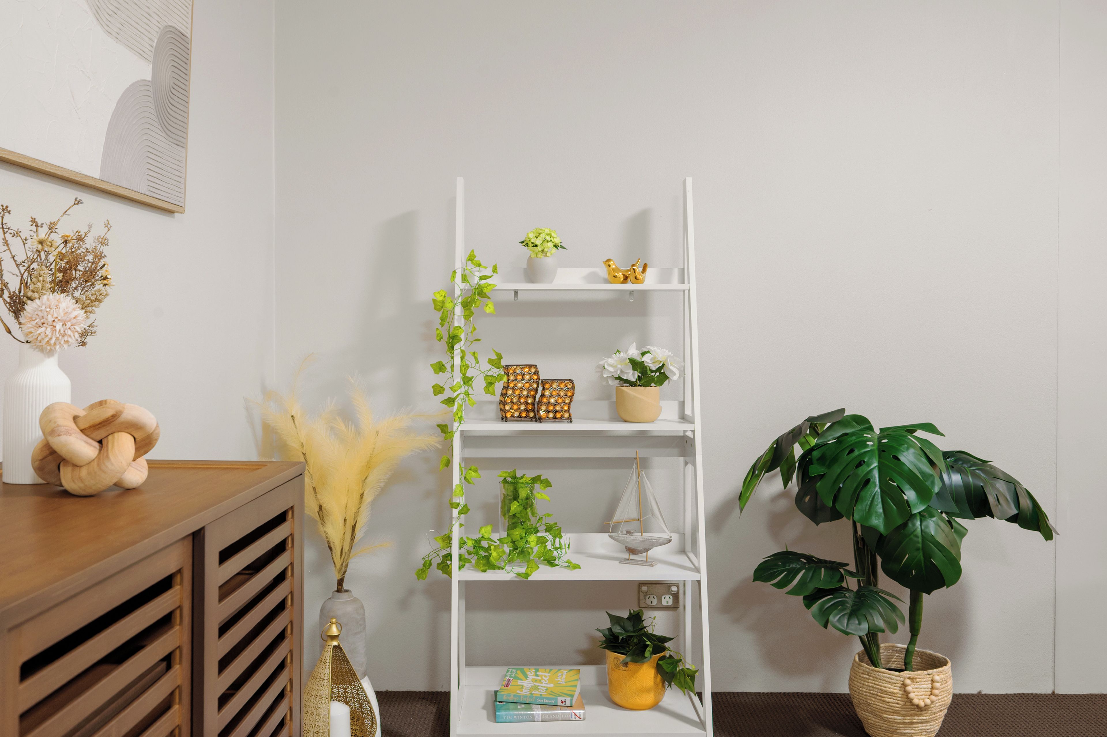 A white shelving unit with various decorative items and plants.