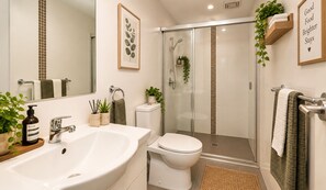 A modern bathroom with a large sink, toilet, and glass shower enclosure.