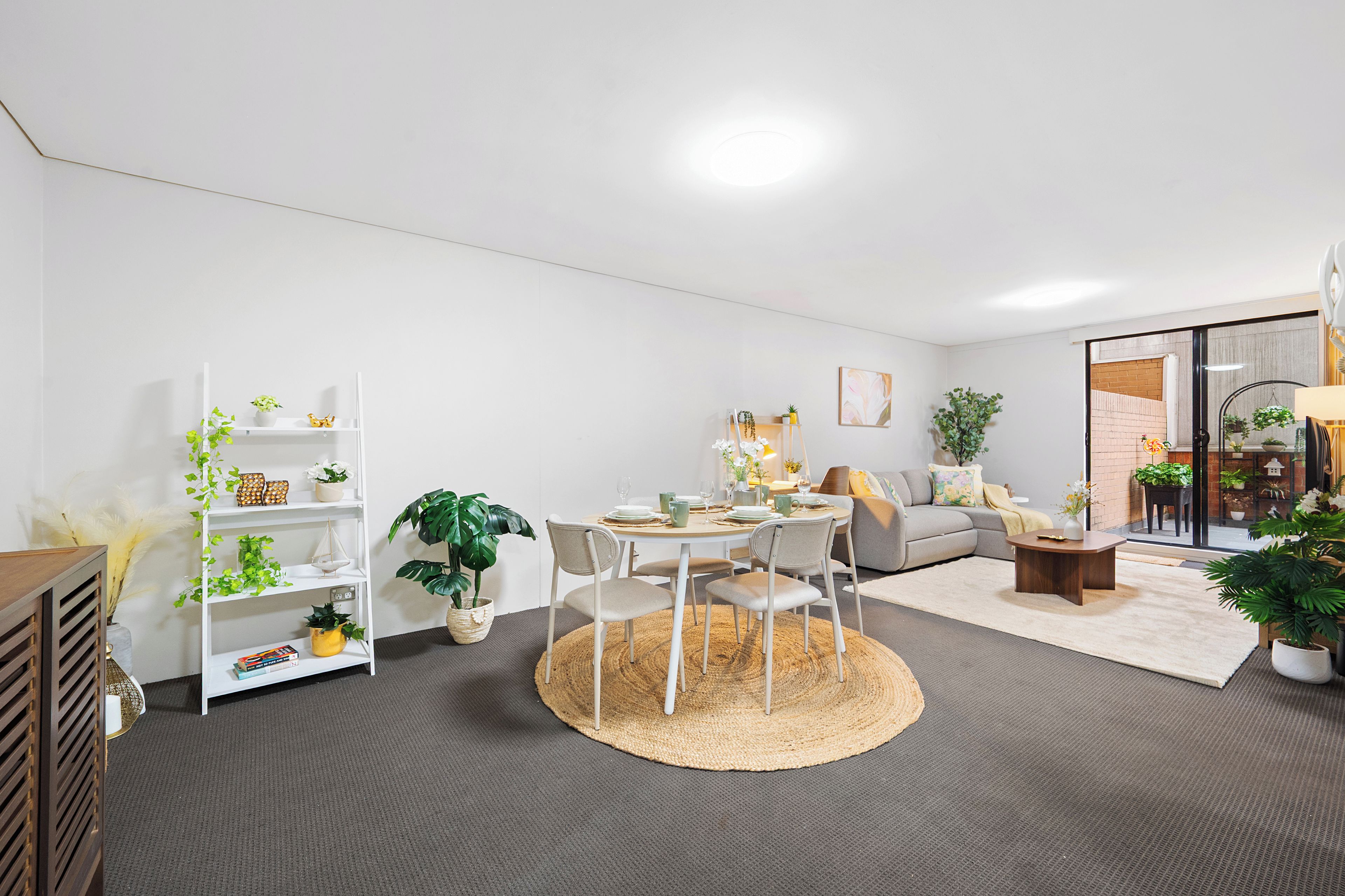 A modern living room with a dining area, white walls, and a large window.