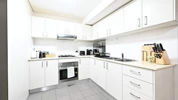 A modern kitchen with white cabinets, a gas stove, a coffee maker, and a knife block.