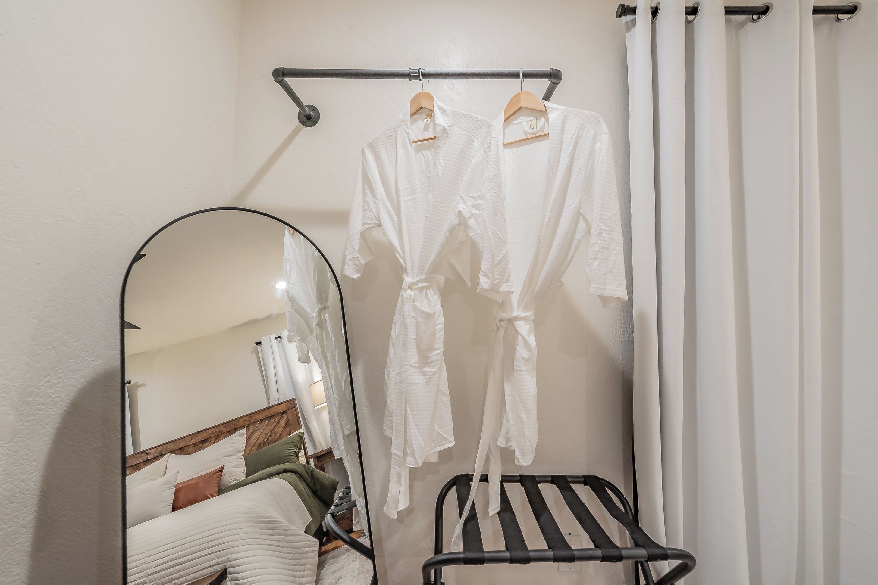 Une salle de bain avec un porte-peignoir suspendu, un miroir et une chaise noire.