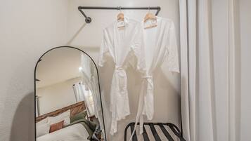 Une salle de bain avec un porte-peignoir suspendu, un miroir et une chaise noire.
