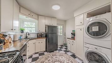 A kitchen with a black refrigerator, a washing machine, and a checkered floor.