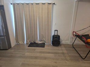 Ein Zimmer mit Holzboden, einer schwarzen Matte, einem Koffer und einem Sportnetz.