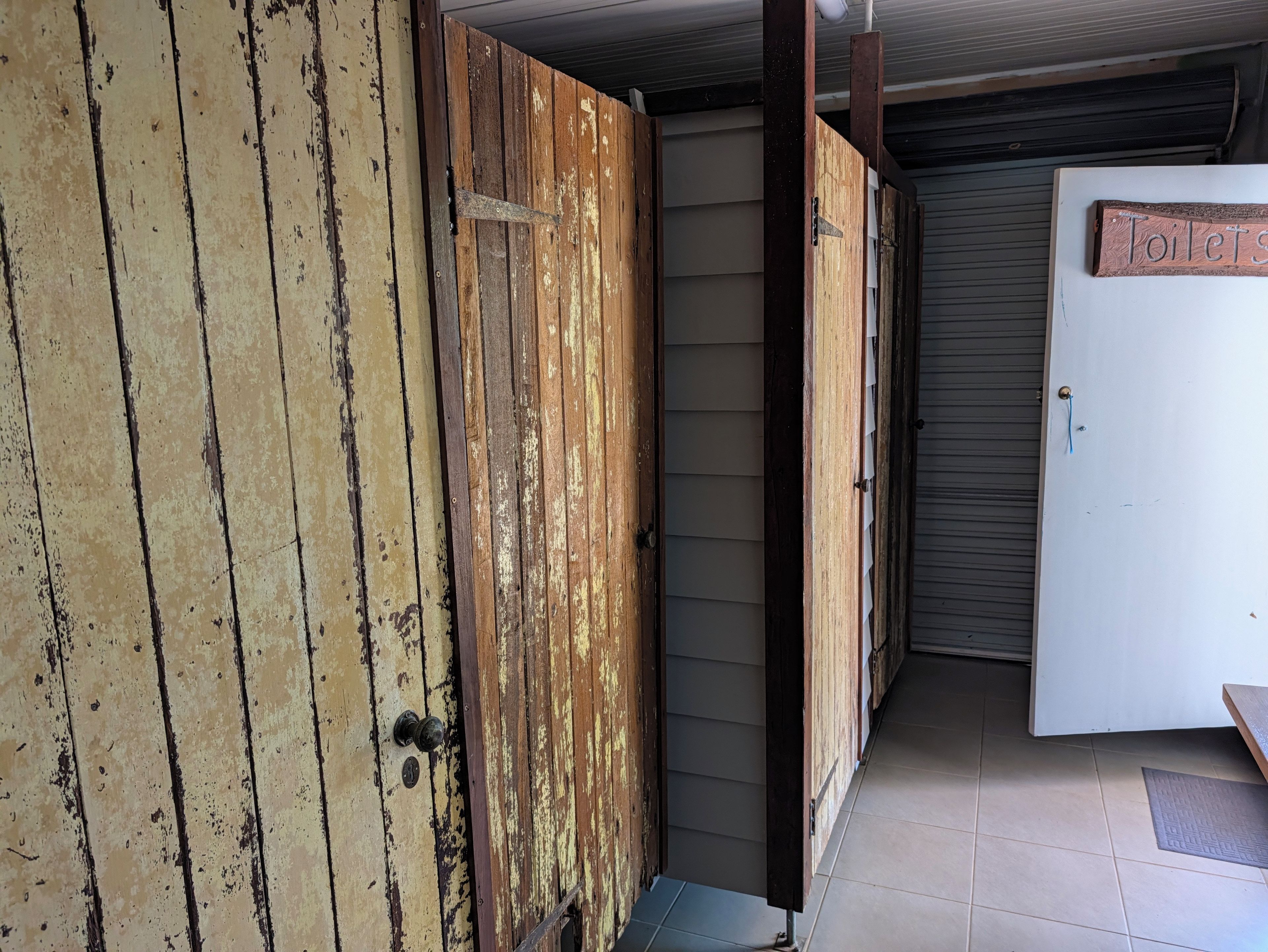 A wooden door with a metal handle and a sign that reads 'toilets' on the wall.