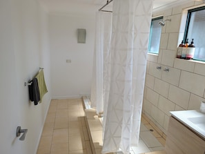 Ein Badezimmer mit Dusche, Waschbecken und Fenster.