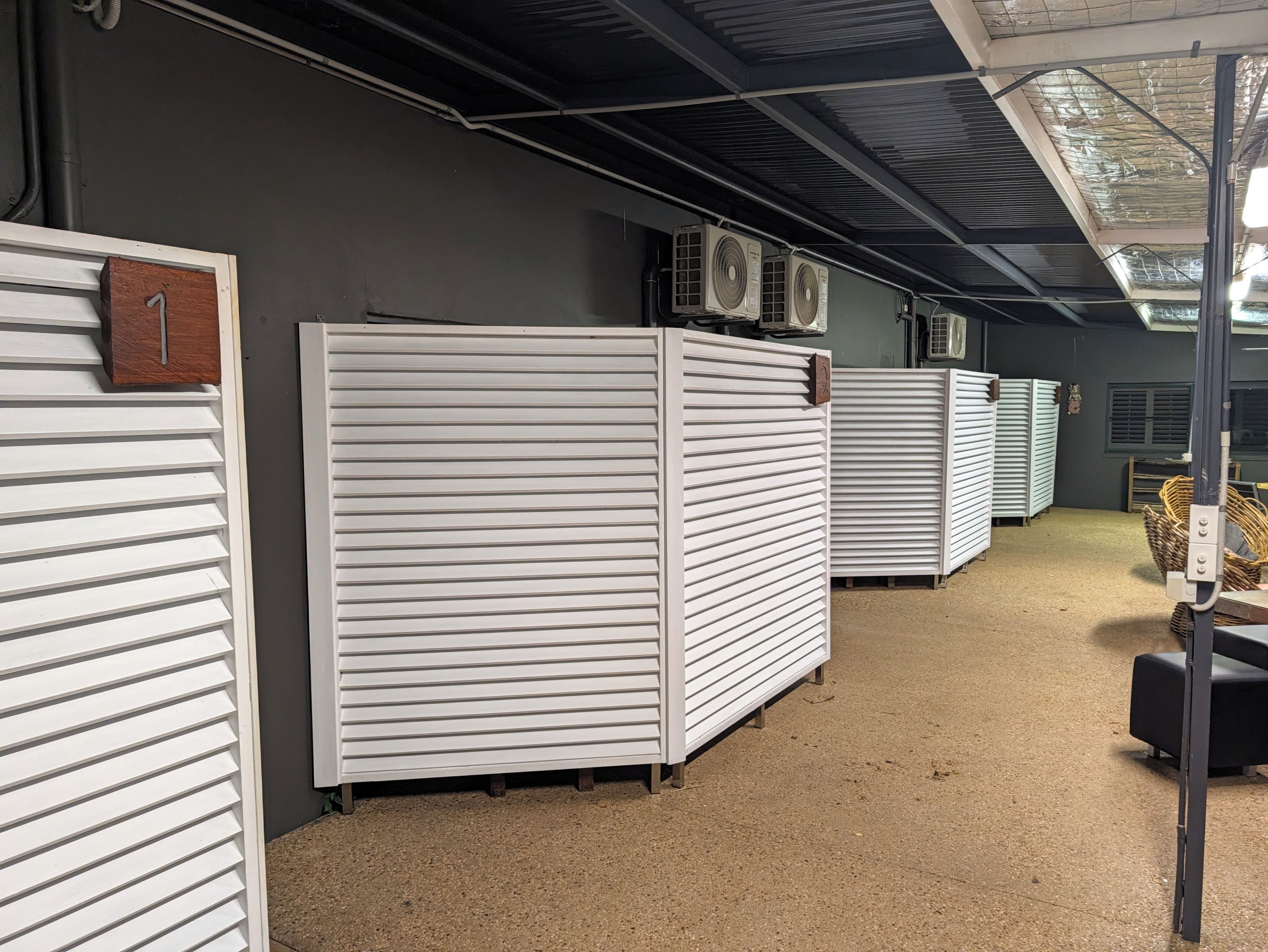 A storage area with metal shutters, a number sign, and industrial fans.