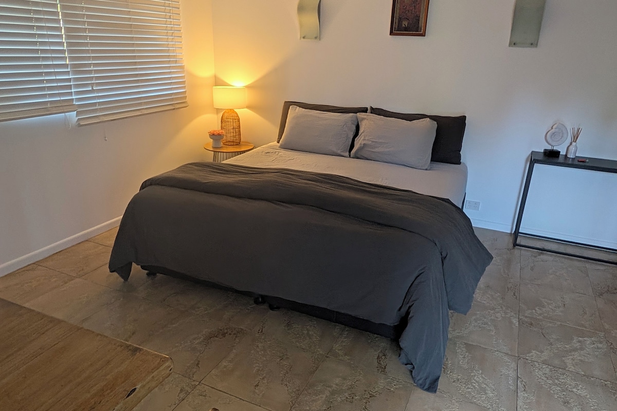 Ein Schlafzimmer mit einem Bett, einem Nachttisch, einer Lampe und einem kleinen Schrank.