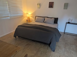 Ein Schlafzimmer mit einem Bett, einem Nachttisch, einer Lampe und einem kleinen Schrank.