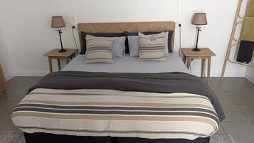 A neatly made bed with a striped blanket, two bedside tables with lamps, and a wooden headboard.