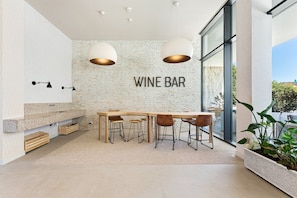 A modern wine bar with a brick wall, wooden table, and bar stools. - GuestReady-Elegant Studio with Luxurious Amenities (Vila Nova de Gaia)