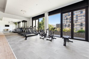 Un gimnasio moderno con equipamiento de ejercicio, amplias ventanas y vistas a la ciudad.