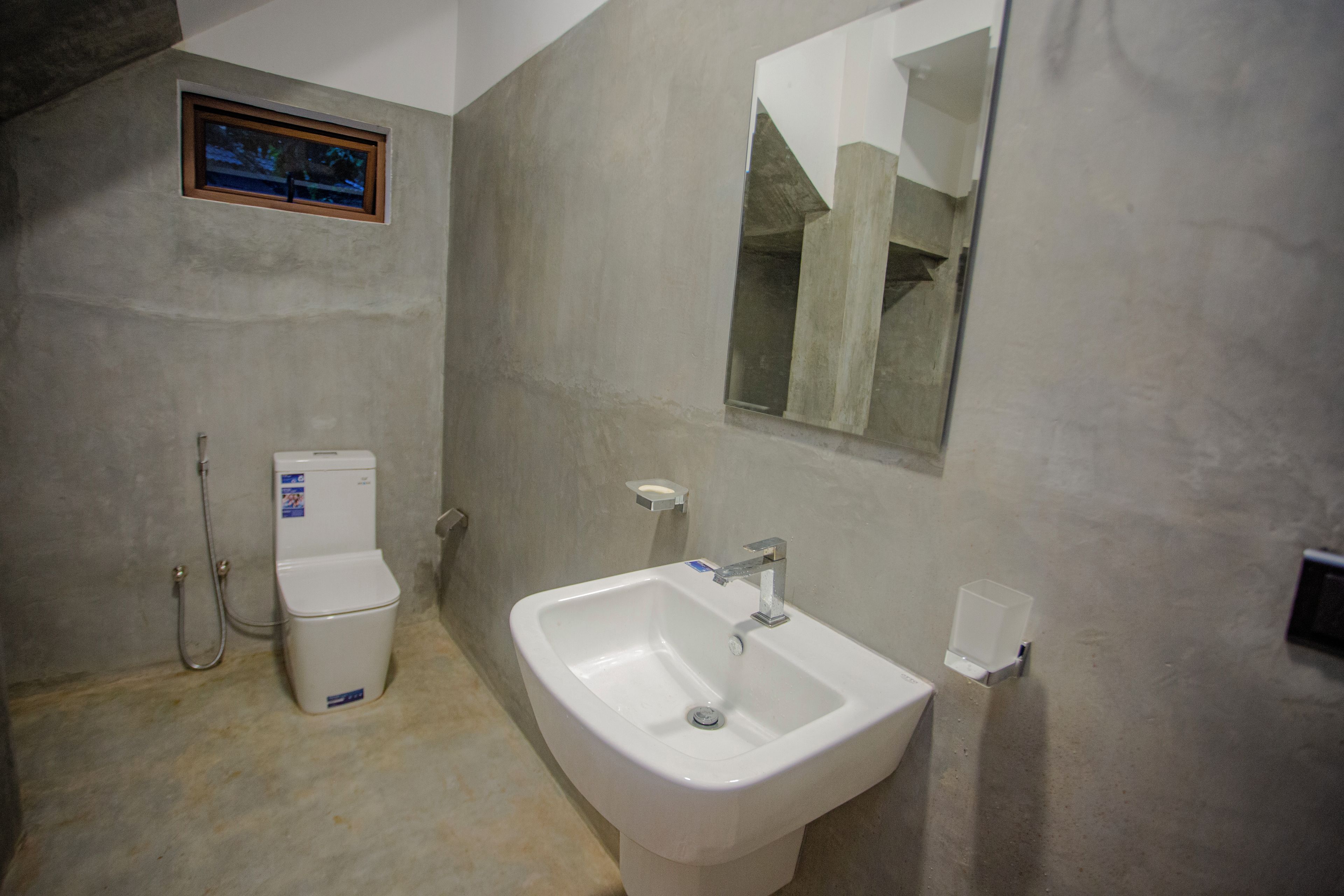 A bathroom with a toilet, sink, and a framed picture on the wall.