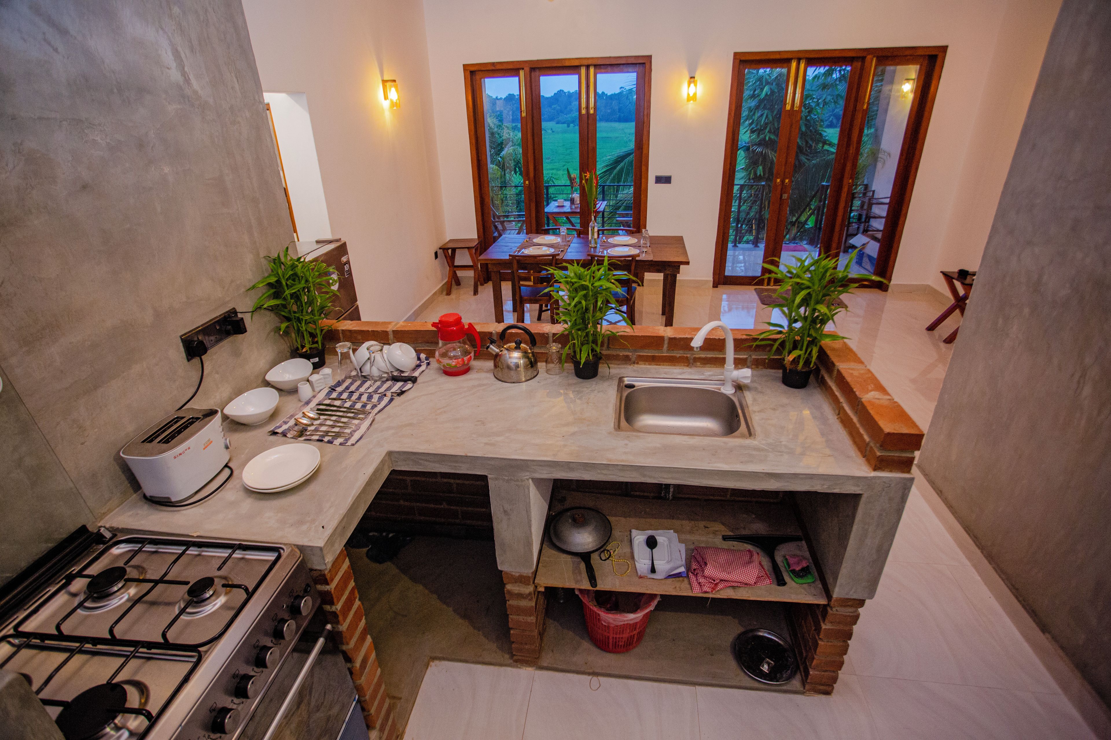 Una cocina compacta con estufa a gas, lavamanos y zona de comedor con mesa y sillas.