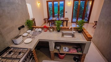 Una cocina compacta con estufa a gas, lavamanos y zona de comedor con mesa y sillas.