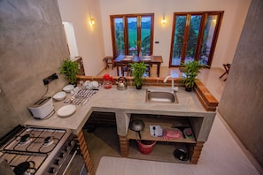 Una cocina compacta con estufa a gas, lavamanos y zona de comedor con mesa y sillas.