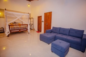 A room with a bed under a canopy, a blue sofa, and a wooden door.