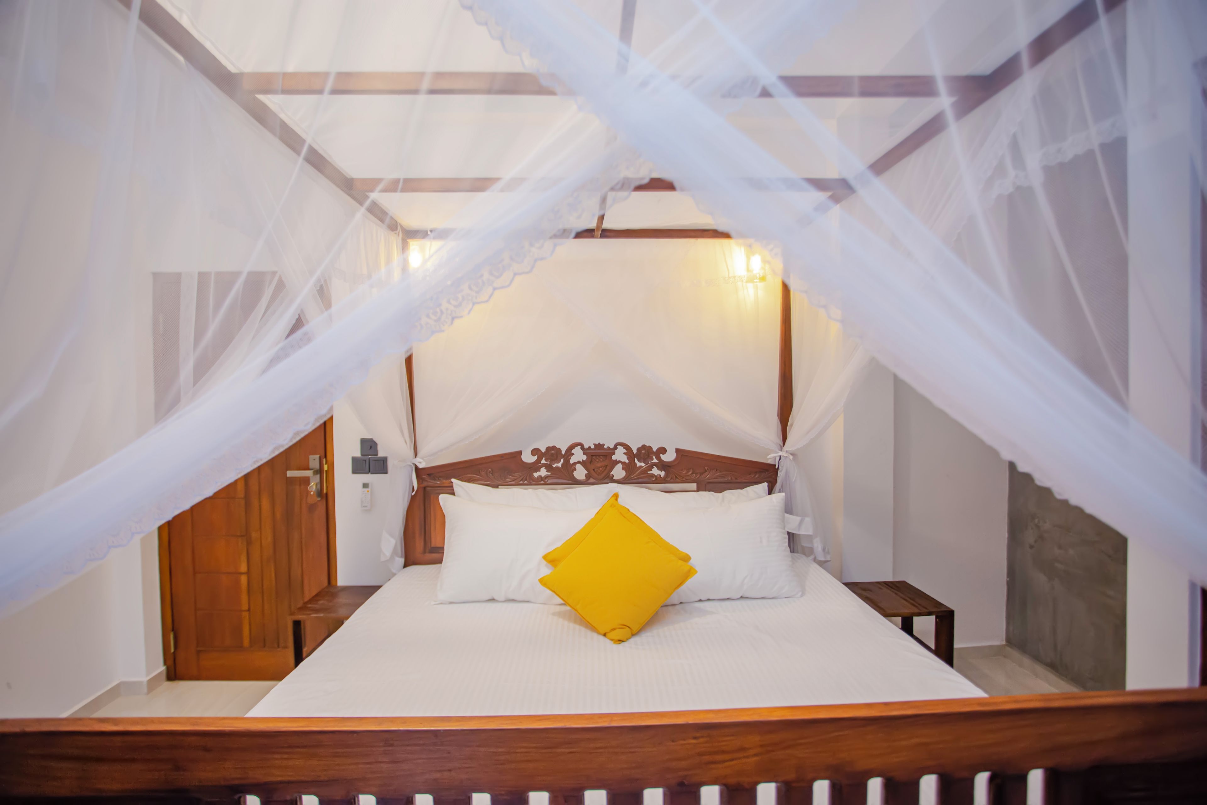 A bed with a canopy, wooden headboard, and white bedding.