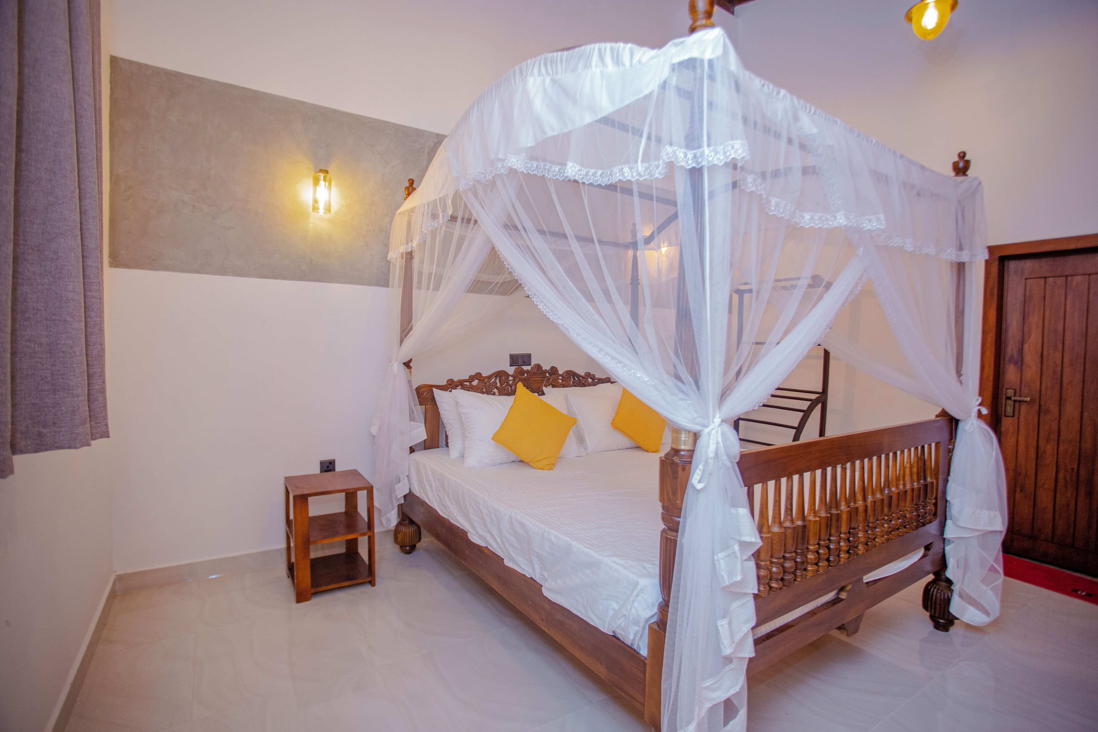 Un dormitorio con cama con dosel, una mesita de noche y una mesilla.
