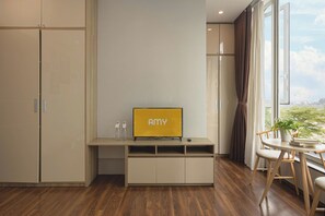 Una camera moderna con TV integrata, pavimento in legno e vista attraverso un'ampia finestra.