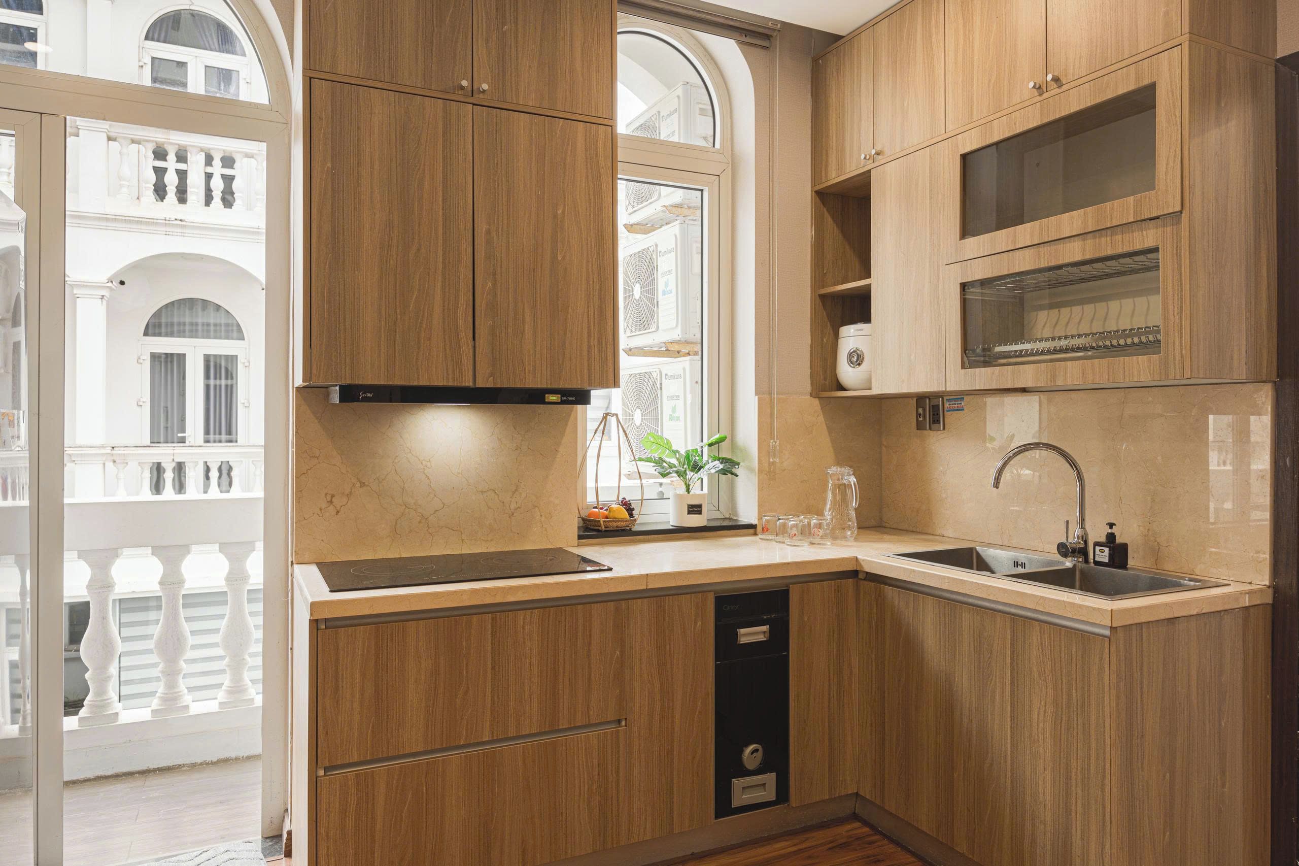 A modern kitchen with wooden cabinetry, a built-in oven, and a window overlooking a balcony.