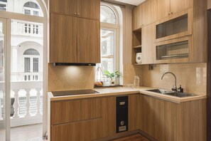 A modern kitchen with wooden cabinetry, a built-in oven, and a window overlooking a balcony.