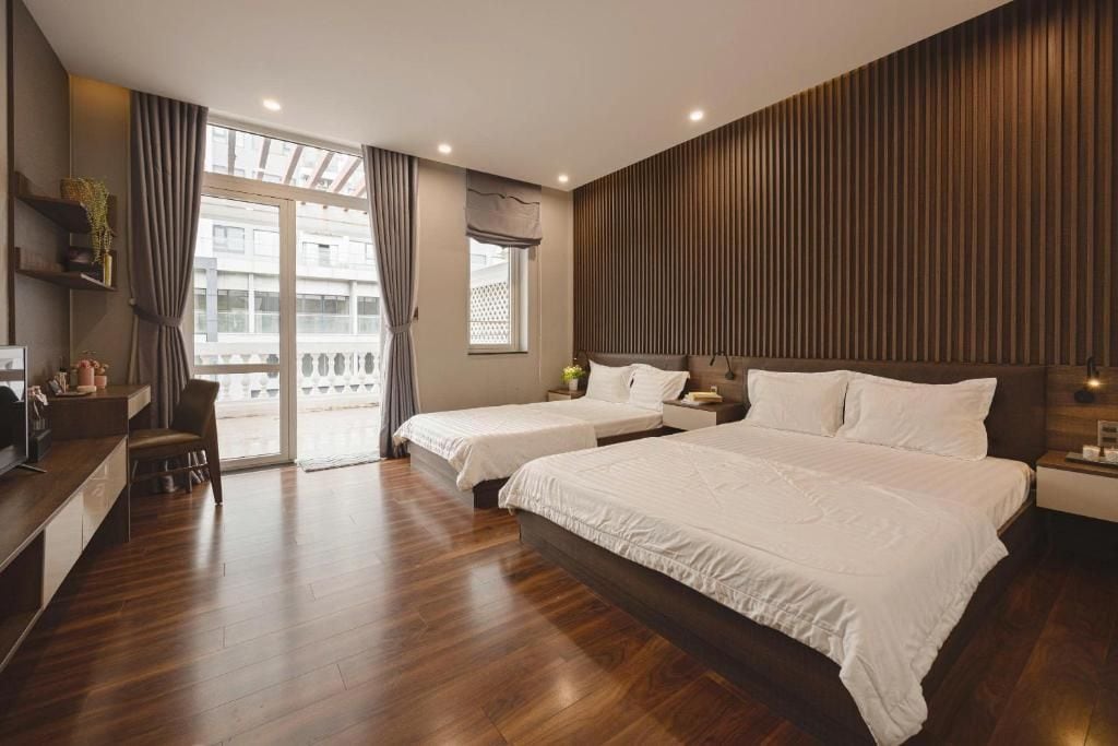 Une chambre d’hôtel avec deux lits, un bureau, une chaise et un balcon avec vue.