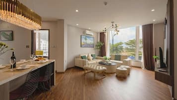 Una sala de estar moderna con un conjunto de sofás, una zona de comedor con sillas y una mesa, y un ventanal con cortinas.