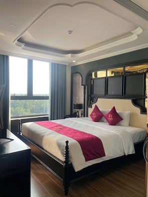Habitación de hotel con una cama grande, un escritorio y vistas a zonas verdes.
