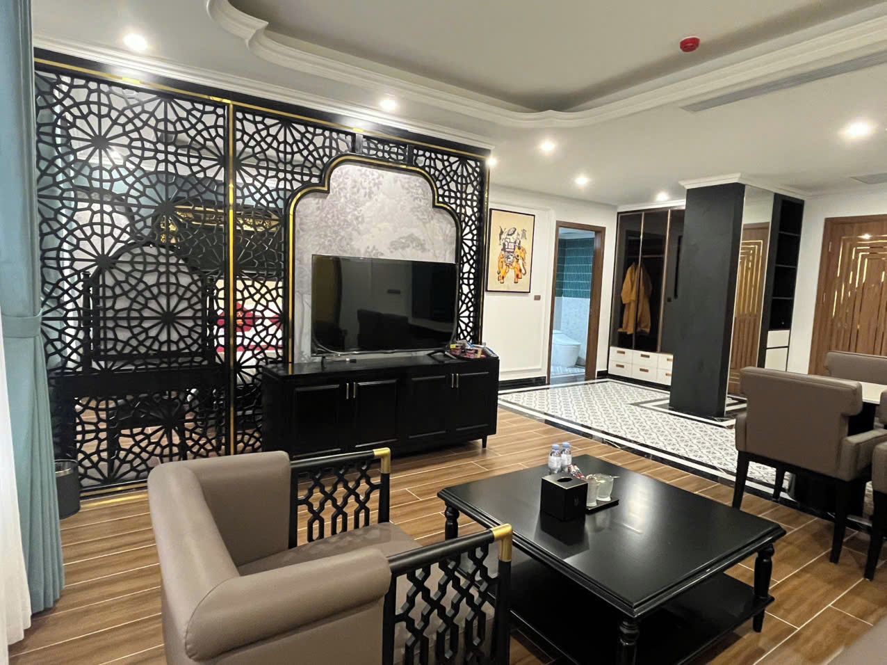 A modern living room with a TV, sofa, coffee table, and a decorative partition.