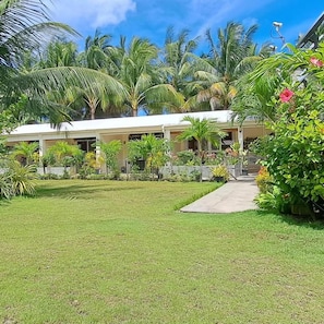 A hotel with a well-maintained lawn, palm trees, and a pathway leading to the building.